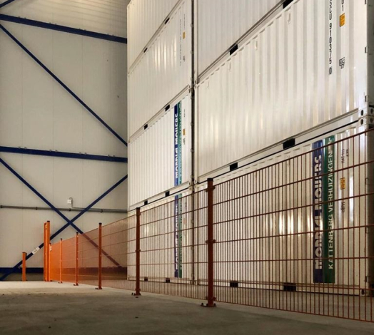 Afbeelding van de binnenkant van een containerloods met opgestapelde containers.