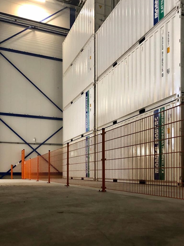 Afbeelding van de binnenkant van een containerloods met opgestapelde containers.